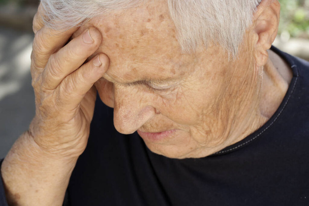 Senior caucasian woman holds her hand to her forehead. Headache, depression or Alzheimer's disease symptoms. - 写真・画像