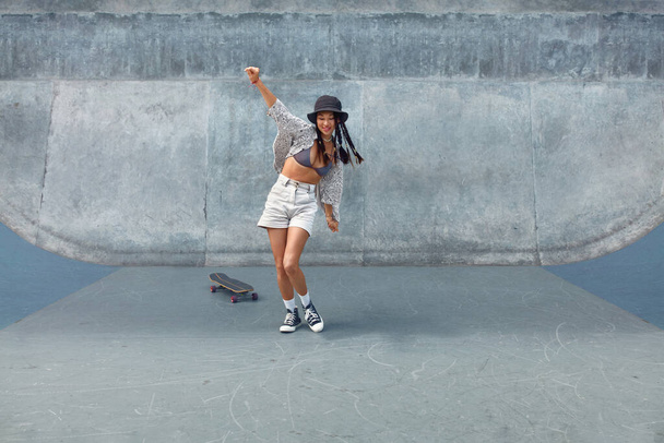 Skateboarding. Asian Girl In Urban Outfit With Skateboard Against Concrete Wall At Skatepark Portrait. City Sport As Hobby Of Active Teens. Skater Subculture And Summer Activity As Lifestyle. - Фото, изображение