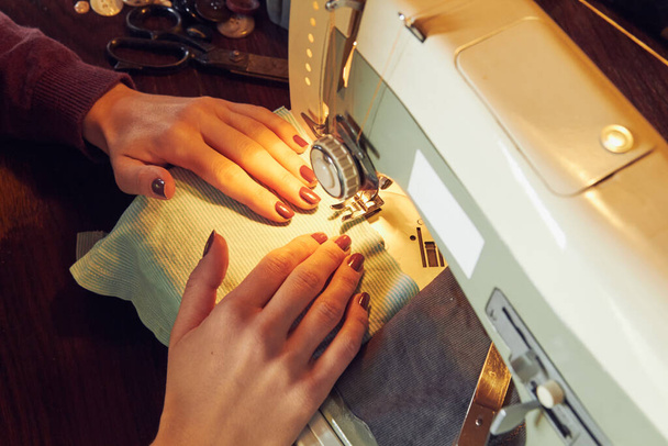 Γυναίκα ράφτης χρησιμοποιώντας ρετρό ραπτομηχανή στο σπίτι, έννοια χόμπι. - Φωτογραφία, εικόνα