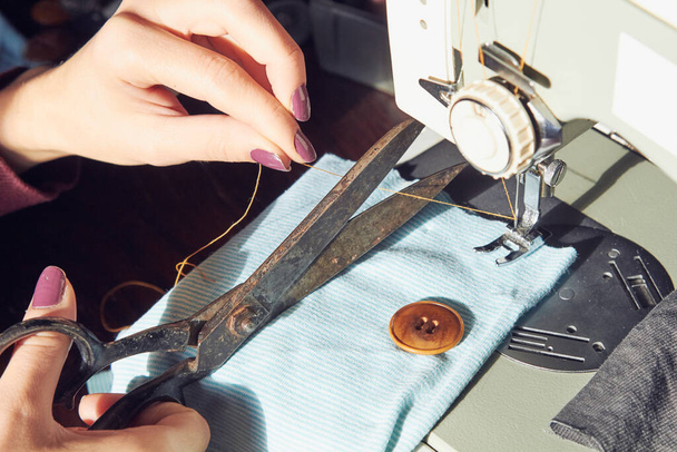 Γυναίκα ράφτης χρησιμοποιώντας ρετρό ραπτομηχανή στο σπίτι, έννοια χόμπι. - Φωτογραφία, εικόνα