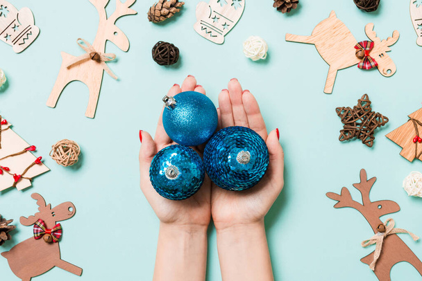 Вид зверху на кулю новорічних кульок у жіночих руках на синьому фоні, зроблені зі святкових прикрас. Концепція різдвяного часу
. - Фото, зображення