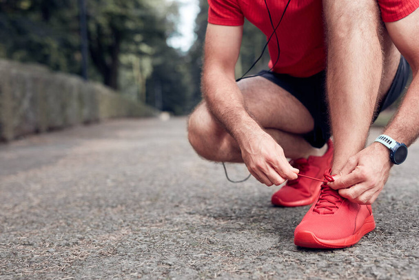 Sporty uomo adulto fare pausa dopo il jogging e l'esercizio nel parco e legare scarpe da corsa. - Foto, immagini