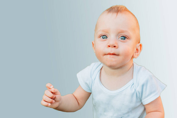 Beautiful one year old baby boy with blue eyes isolated on blue background - Fotografie, Obrázek