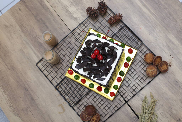 Zoete zelfgemaakte taart versierd met kersen en chocolade op houten tafel, close-up schot - Foto, afbeelding