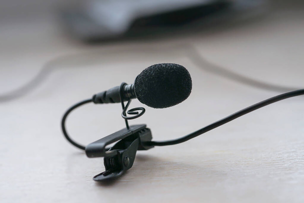 The lavalier microphone lies on a table with a clothespin for attaching. close-up - 写真・画像
