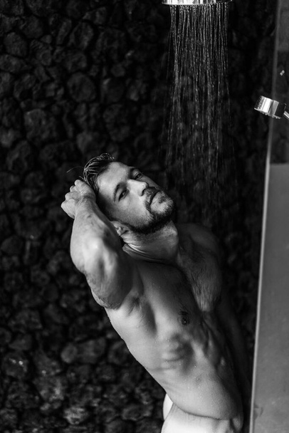 Man taking a shower washing hair with shampoo product under wate - 写真・画像