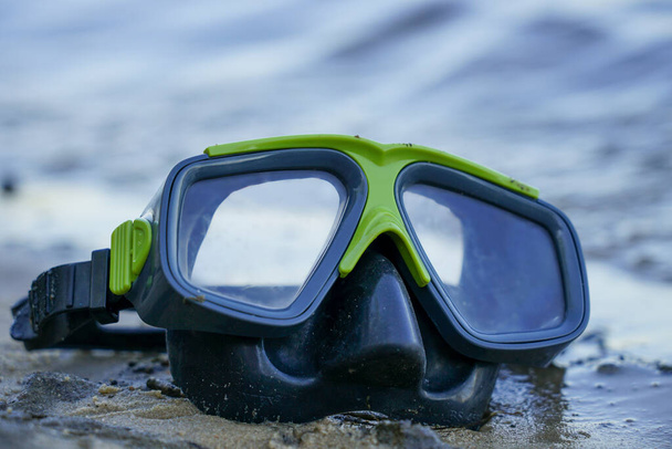 máscara para bucear se encuentra en la arena, la orilla contra el fondo de la ola - Foto, Imagen