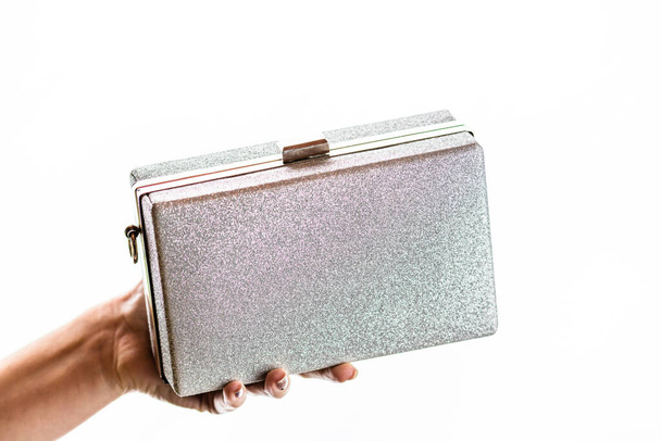 Woman hand holding glittery silver clutch bag isolated on white background with copy space. - Foto, Imagem