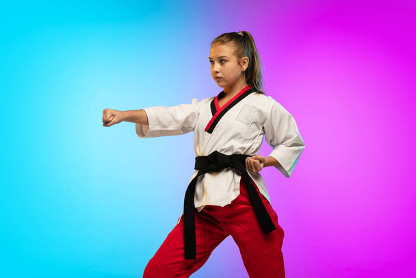 Karate, taekwondo girl with black belt isolated on gradient background in neon light - Photo, Image