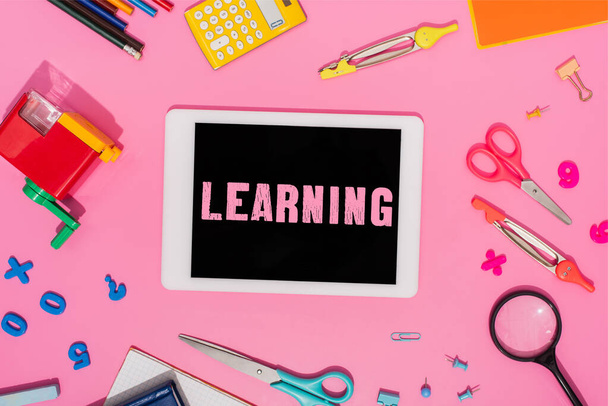 vista superior de la tableta digital con letras de aprendizaje en la pantalla cerca de papelería escolar en rosa  - Foto, Imagen