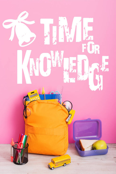 keltainen reppu koulutarvikkeita, lounas laatikko, lelu koulubussi ja kynä haltija huopakynät lähellä aikaa tiedon kirjoitus vaaleanpunainen - Valokuva, kuva