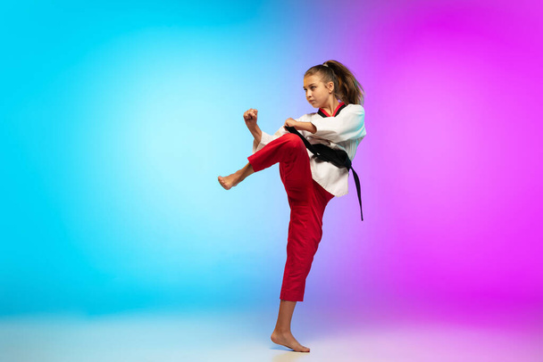 Karate, taekwondo girl with black belt isolated on gradient background in neon light - Foto, Imagem