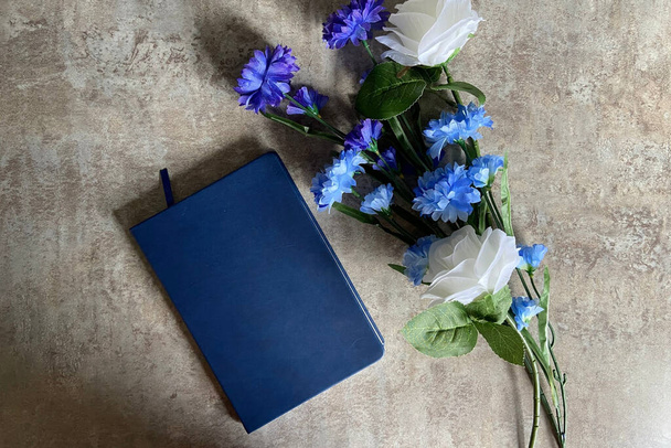 heller und luftiger Hintergrund mit Blumen und Journal auf Beton - Foto, Bild
