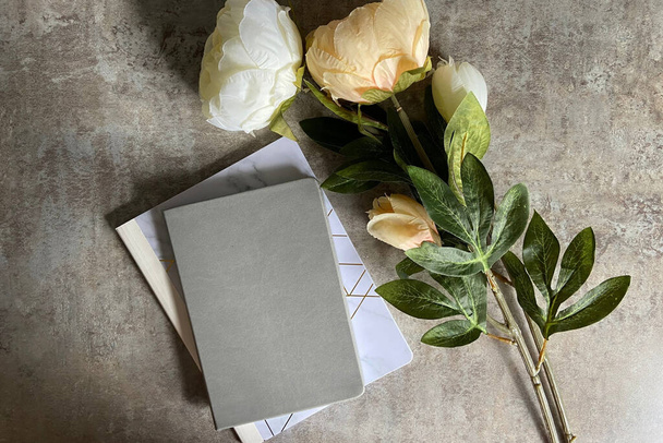 light and airy background with flowers and journal on concrete - Photo, Image