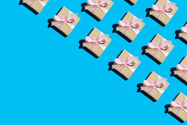Ελάχιστη σύνθεση φόντο των Χριστουγέννων κουτί δώρου. Κουτί δώρου μοτίβο με ροζ φιόγκο σε μπλε φόντο πάνω όψη επίπεδη lay. Διακοπές έννοια νέο έτος ή Χριστούγεννα κουτί δώρου παρουσιάζει Χριστούγεννα διακοπές. - Φωτογραφία, εικόνα