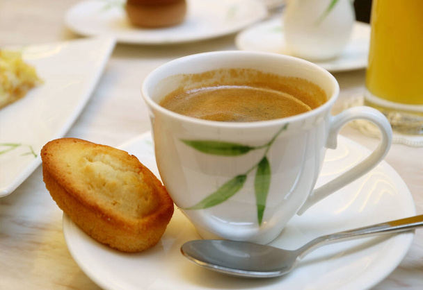 Çay masasında sergilenen Fransız bademli keki ile bir fincan sıcak kahve. - Fotoğraf, Görsel