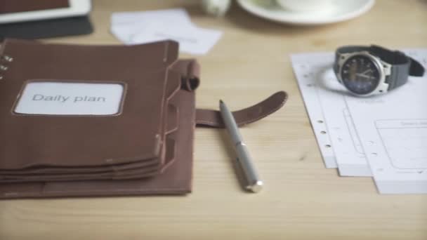 Lähikuva laukaus vaaleanruskea nahka muistilehtiö päivittäin suunnittelija tapana tracker bullet päiväkirja matkapuhelin puinen työpöytä - Materiaali, video