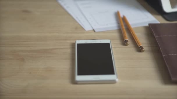 Close-up shot van mobiele telefoon licht bruin leer dagelijkse planner kogel dagboek gewoonte tracker notitieblok op houten werktafel - Video