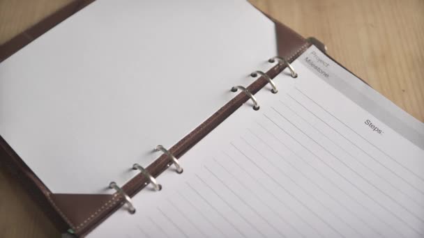 Plan rapproché des mains de femme ouvrant un classeur en acier métallique sur un carnet de notes en cuir carnet de notes agenda organisateur quotidien - Séquence, vidéo