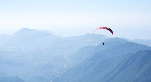Paraglider flying over mountains near Kemer, a seaside resort on the Turkish Riviera in Antalya Province, Turkey - Фото, изображение