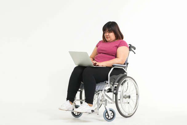 Fat Asian woman sitting and working on a wheelchair Cannot walk due to health problems and body weight. Weight loss concepts. copy space - Photo, image