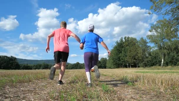 Felnőtt sport heteroszexuális pár fut kéz a kézben az őszi természetben. Imádok együtt sportolni. Lassú mozgás. - Felvétel, videó