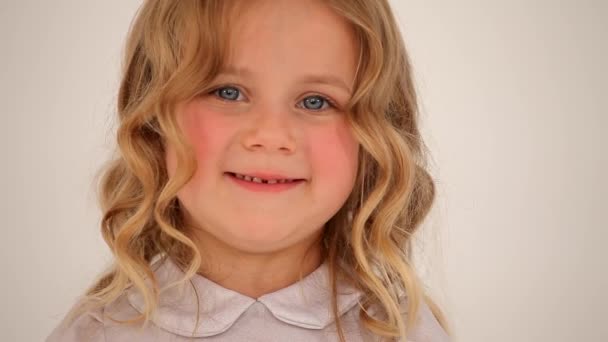 Lähikuva laukaus söpö pieni mukava pieni tyttö lapsi lapsi lapsi ruusuinen posket vaalea kihara tukka näköinen hymyillen kameran - Materiaali, video