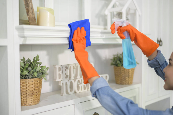 A woman with cleaning gloves using alcohol spray sanitiser to cleaning house, healthy and medical, covid-19 protection at home concept . - Foto, Bild