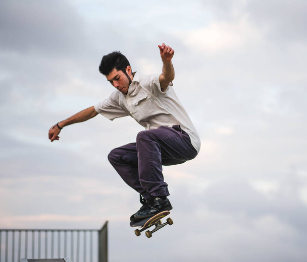 Un joven caucásico haciendo trucos con un monopatín en un parque de skate - Foto, Imagen