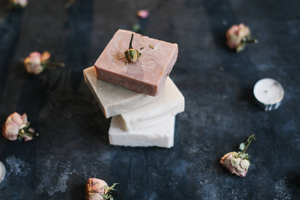 Homemade floral soap. Natural soap and rose flowers on dark background. Spa concept, body care products. Flat lay, top view - Fotoğraf, Görsel