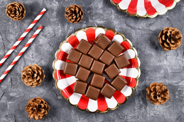 Top view of German traditional sweets called 'Dominosteine', gingerbread, jelly and marzipan layered glazed food sold around Christmas season on red and white striped plate - Foto, afbeelding
