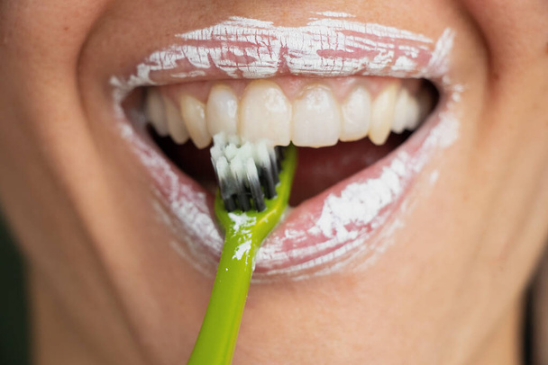 labios femeninos untados con pasta de dientes blanca y un cepillo de dientes, cepillarse los dientes - Foto, Imagen