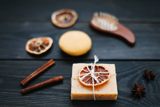 Natural handmade soap with dried slices of oranges and cinnamon on a dark background. Concept of Spa, body and skin care.   - Фото, зображення