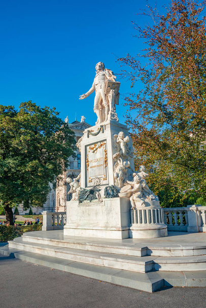 Warm sunset over Mozart monument in front of Palmenhaus, near Neue Burg and Hofburg Palaces garden, in historical downtown of Vienna, Austria at sunny day, blue sky in Autumn colors - Photo, Image