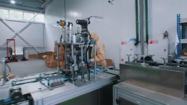 Βιομηχανική παραγωγή προστατευτικών ιατρικών μασκών - εργαζόμενος με προστατευτική ενδυμασία και γάντια συσκευάζει τις μάσκες μαζί - Πλάνα, βίντεο