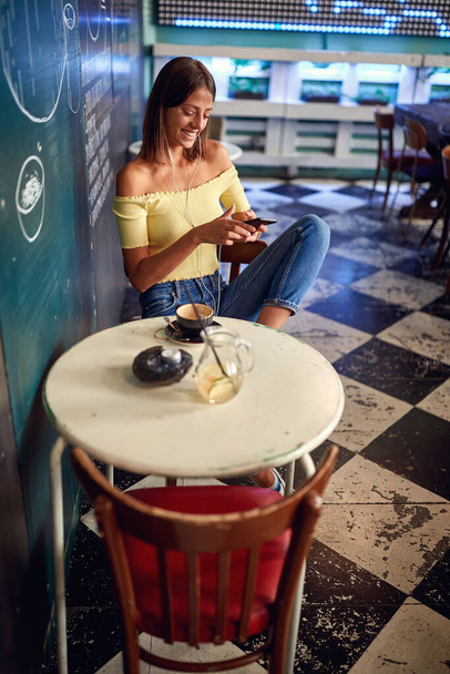 Young girl having coffee in a bar while texting - Photo, image
