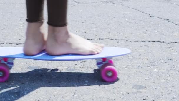 Девушка на скейтборде толкает себя по асфальтовой дороге. ProRes 422 - Кадры, видео