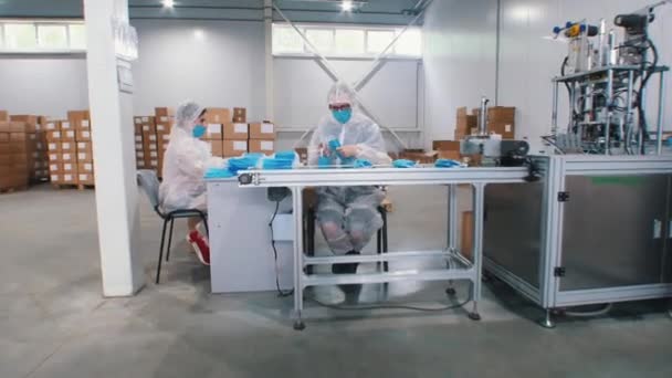 Průmyslová výroba modrých ochranných lékařských masek - pracovníci společně balí masky - Záběry, video