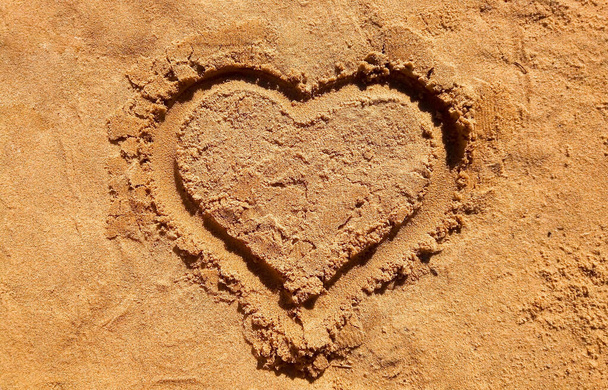 Hart getekend hart symbool op zand, zeekust. Gouden zandstrand close-up, zomervakantie concept. Toeristische reisbanner ontwerp sjabloon, kopieerruimte. Liefdessymbool, hartvorm - Foto, afbeelding
