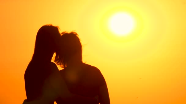 Viajeros disfrutando de la vista del amanecer. Una hija adulta abraza a su madre mirando el amanecer. Escena cinematográfica de la salida del sol con dos siluetas femeninas sobre el fondo de la puesta del sol. Concepto de vacaciones. Vista trasera - Imágenes, Vídeo