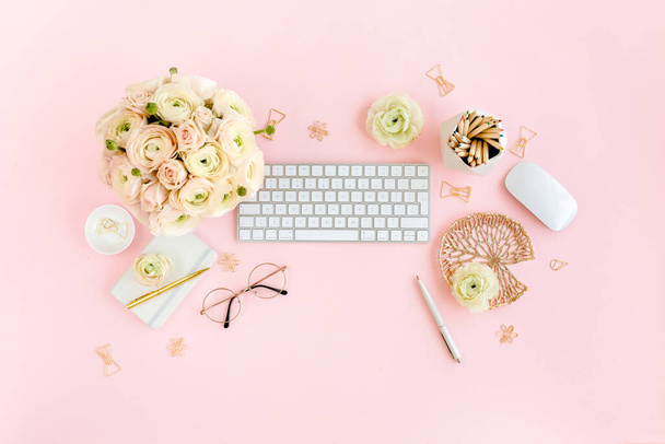 Stylized, pink womens home office desk. Workspace with computer, bouquet ranunculus and roses, clipboard on pink background. Flat lay. Top view. - Foto, immagini