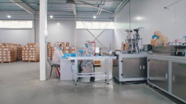 Production industrielle de masques médicaux de protection sur l'usine - travailleurs emballant les masques ensemble - Séquence, vidéo