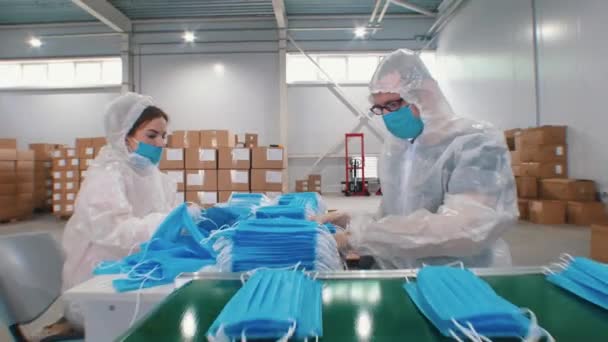 Průmyslová výroba ochranných masek v továrně - pracovníci balící masky dohromady - Záběry, video