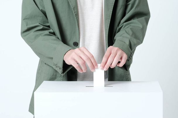 Manos de un joven que pone una boleta en una urna electoral - Foto, imagen