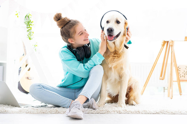 Happy girl holding headphones on dog - 写真・画像