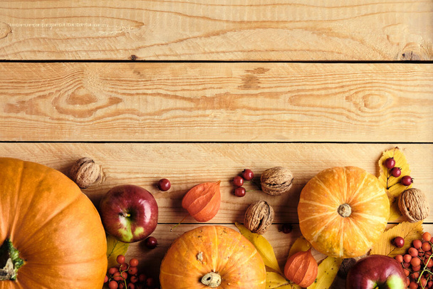 Happy Thanksgiving concept. Autumn composition with plate, ripe orange pumpkins, fallen leaves, fruits, nuts on rustic wooden table. Flat lay, top view, copy space. Thanksgiving greeting card mockup. - Photo, image