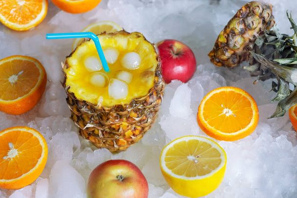Fruchtcocktail mit Ananas, Eiswürfeln und Zitrusfrüchten auf dem Eis - Foto, Bild