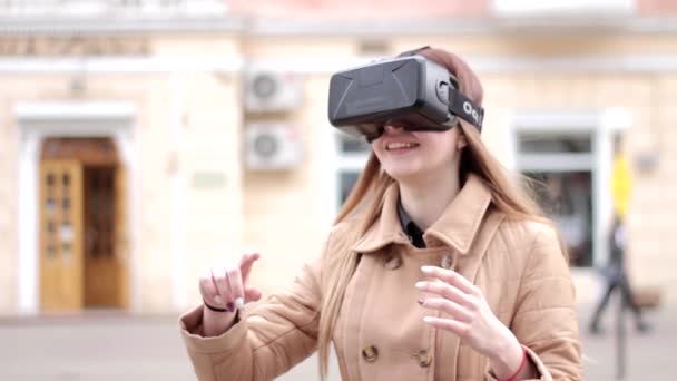 Junge Frau mit Virtual-Reality-Brille aus der Cyberspace-Technologie und Headset-Brille in beigem Outfit amüsiert sich draußen auf der Straße - Filmmaterial, Video