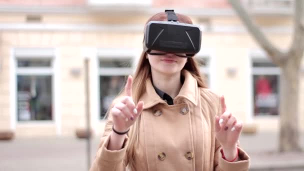 Mujer joven y feliz con tecnología de ciberespacio vr gafas de realidad virtual de auriculares que se divierten al aire libre en la calle en abrigo de outwear beige - Metraje, vídeo