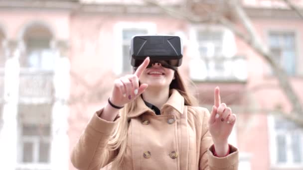 Mujer feliz joven con tecnología de ciberespacio vr gafas de realidad virtual auriculares divertirse al aire libre en la calle en abrigo de outwear beige - Imágenes, Vídeo